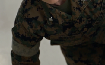 Female service member in camouflage looking up from the mess hall floor