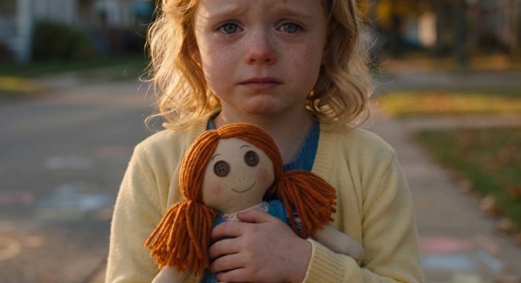 Young Layla holding her handmade doll on a quiet neighborhood street.